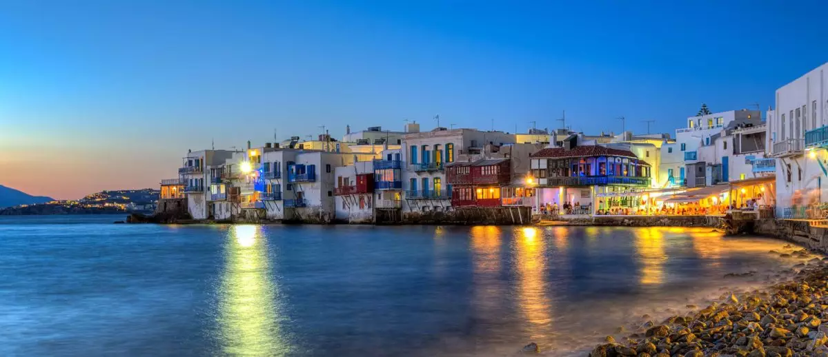 Golden sunset over Mykonos beach with clear blue waters